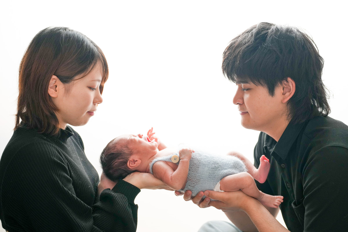白背景で赤ちゃんを囲むニューボーン撮影のFamily Book